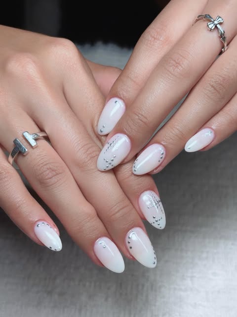 Milky white almond nails with tiny silver studs.